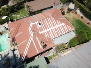 Aerial view of a red corrugated roof with white membrane strips applied over the seams