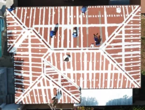 Top-down view of workers sealing the seams of a corrugated roof before coating