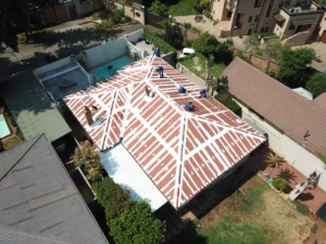 Aerial view of a team sealing the seams of a red corrugated roof