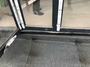 Torch-on waterproofing membrane sealed against a glass door threshold