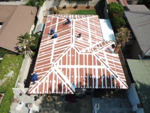 Aerial view of workers applying white seam sealing across a corrugated house roof