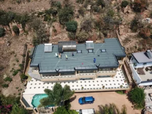 Aerial view of workers waterproofing the flat roof of a hillside home